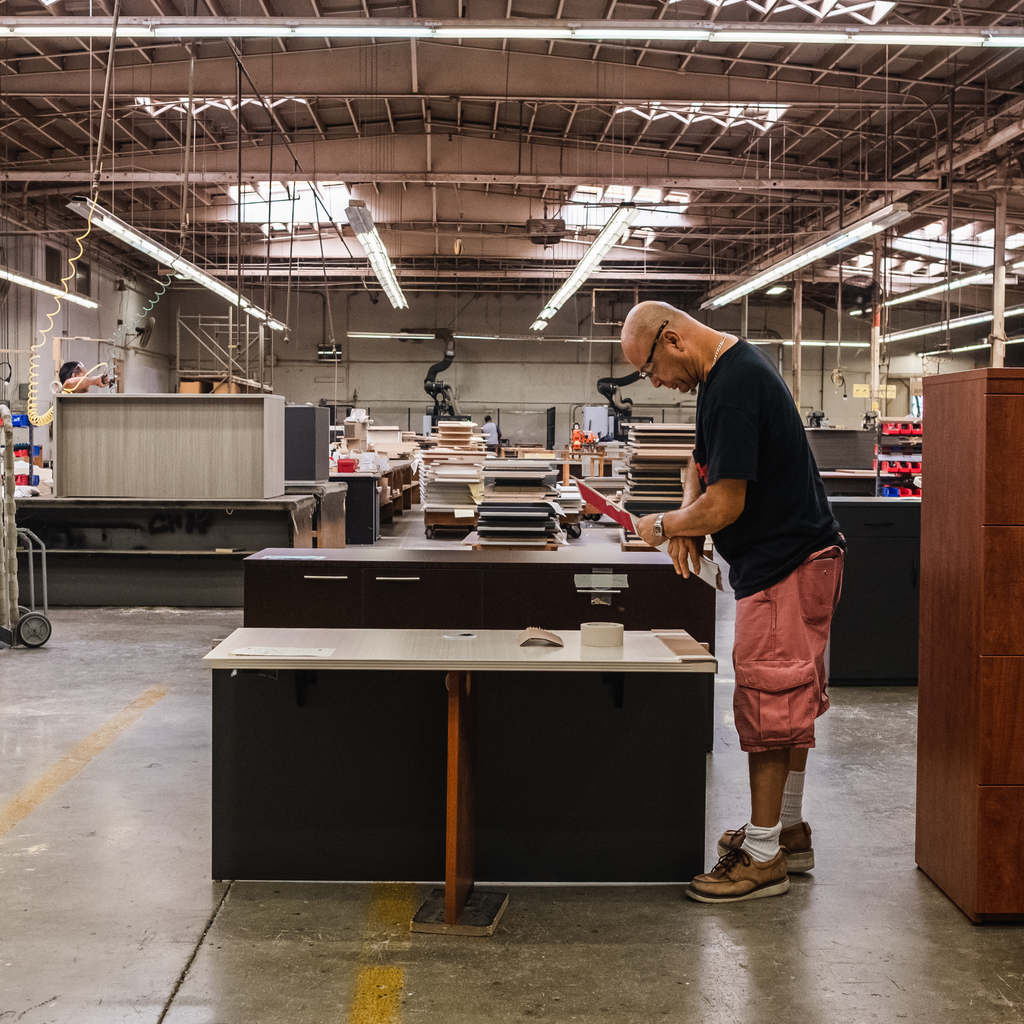 Assembly worker finishing a desk in warehouse