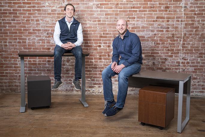 Porvata co-founders Nick and Will sitting on desks